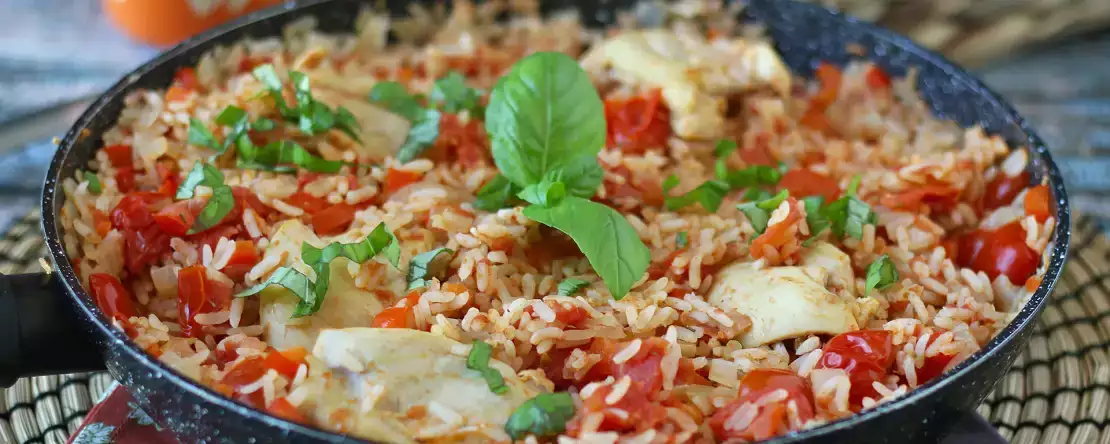 Satu panci berisi ayam, nasi dengan saus tomat dan paprika